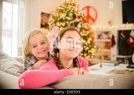 Portrait of teenage girl and brother leaning on sofa at christmas Stock Photo