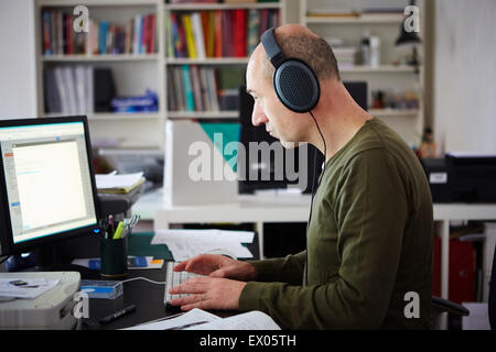 Mature man working in creative studio wearing headphones Stock Photo