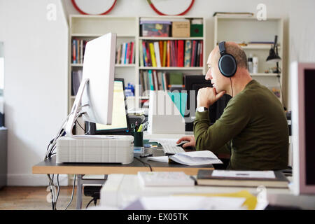 Mature man working in creative studio wearing headphones Stock Photo