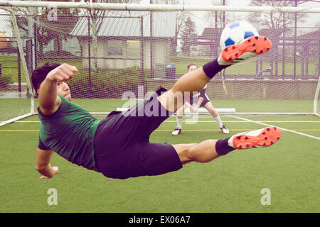 Young male soccer player kicking ball toward goal Stock Photo