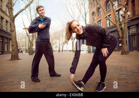 Male and female runners warming up on tree lined street, Pioneer Square, Seattle, USA Stock Photo