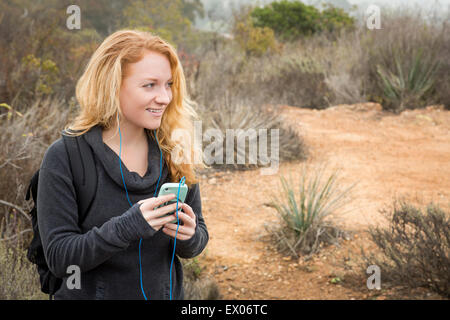 Young female hiker choosing music on smartphone Stock Photo