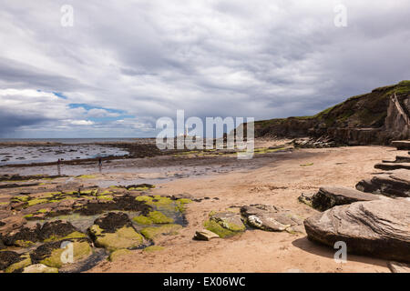 Two walkers on the beach at Collywell Bay, Seaton Sluice, Northumberland with a view of St Mary's Island and Lighthouse at low tide Stock Photo