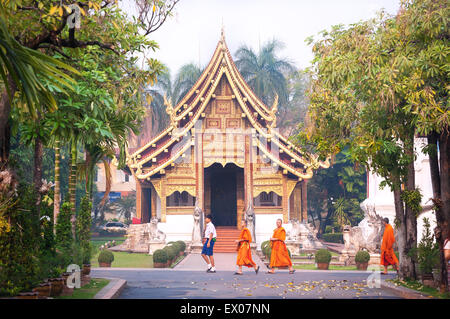 Monks and schoolboys walk past Viharn Lai Kham at Wat Phra Singh, Chiang Mai, Thailand Stock Photo