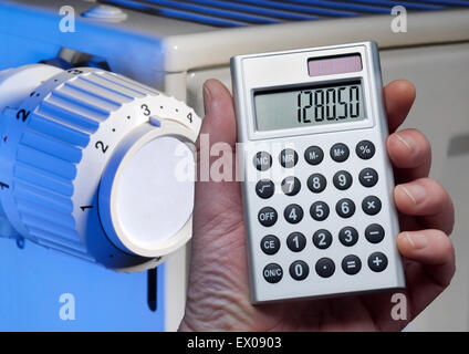 Hand holding a calculator in front of a radiator. Stock Photo
