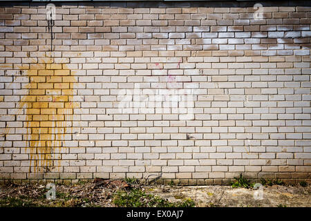 Old weathered wall of bricks with a splash of yellow paint Stock Photo