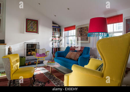 Bold blue sofa, Julep chair and Eames wire rocking chair in living room with aboriginal wall art Stock Photo