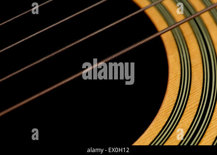 An angled macro shot of acoustic guitar strings and the wood around the sound hole of the guitar. Stock Photo