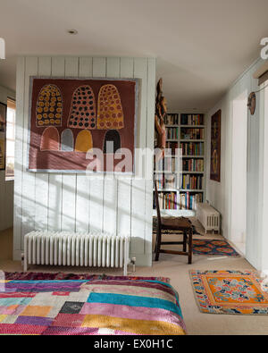 Painting on wall by aboriginal artist Queenie Mackenzie Nakarra in bedroom with antique quilt from Bihar, India Stock Photo