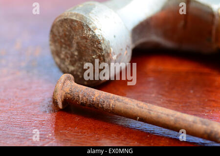 Macro shot of an old rusty nail and a hammer on a table Stock Photo