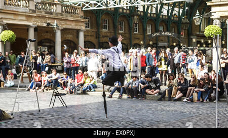 Covent Garden, piazza, London UK: a street entertainer walks across a tight rope, with tourists and local people watching. Stock Photo