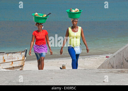 Two Creole women carrying plastic tubs with coconuts out of the harbour of Tarrafal on the island Santiago, Cape Verde, Africa Stock Photo