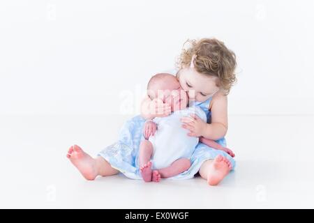Sweet toddler girl kissing her newborn baby brother Stock Photo