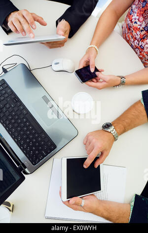 Portrait of casual executives using different electronic objects at a meeting. Stock Photo
