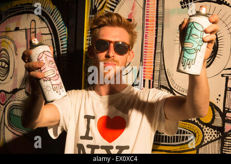 London, UK. 2 July 2015. Belgian artist Joachim poses with spray cans. GraffitiStreet.com, the online street art gallery, are back for a second year to present their latest group show titled ‘Underground’ on 2 July 2015 in Shoreditch. With participating street and graffiti artists Pichi & Avo (Spain), L7m (Brazil), Bordalo II (Portugal), Hunto (Italy), Pahnl (UK), Bisser (Belgium), My Dog Sighs (UK), JPS (UK), Art is tra$h (Spain), Nils Westergard (US), Joachim (Belgium) and 3F (UK). Stock Photo