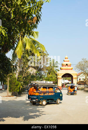 A car load of monks drives off from Wat Manoran. Luang Prabang, Laos Stock Photo