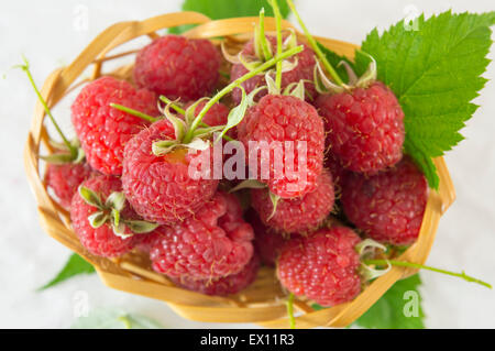 Fresh raspberries in wooden basket on white background Stock Photo