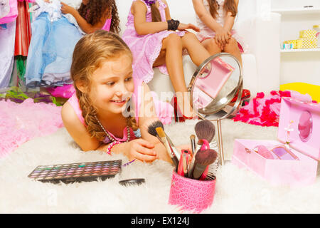 Girl laying on fluffy white carpet with brushes Stock Photo