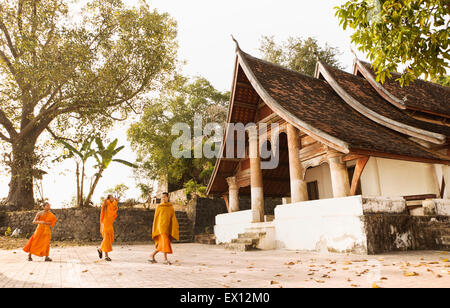 Young monks walk by Wat Siphoutthabat Thipphuramm at dawn. Luang Prabang, Laos. Stock Photo