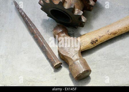 Close up shot of an old rusty ball peen hammer, chisel  and metal part over a concrete surface with natural light Stock Photo
