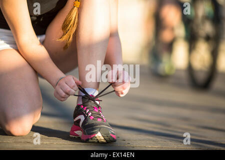 Girl is tying close-up the laces sports shoe before running. Running, healthy lifestyle. Stock Photo