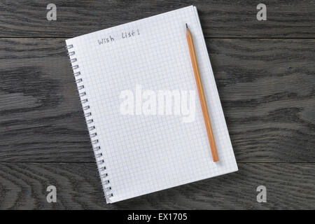 blank notepad with chequered pages and phrase wish list on gray wood table and pencil Stock Photo