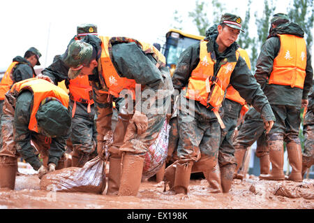 Sunan, China's Gansu Province. 4th July, 2015. Armed policemen clear off mud on a road in Sunan County, northwest China's Gansu Province, July 4, 2015. A heavy rainfall caused landslide in Sunan on Saturday, damaging 63 houses. Credit:  Wu Xuefeng/Xinhua/Alamy Live News Stock Photo