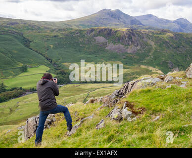 A photographer shooting photos of Scafell Pike and Scafell, near Hardknott Pass Roman Fort in the Lake District, England. Stock Photo