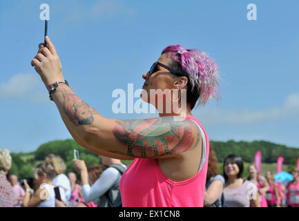 Brighton UK Saturday 4th July 2015 - A young woman with tattoos takes a selfie photograph at the Cancer Research UK Race for Life Pretty Muddy event held in Stanmer Park Brighton today . They had to take part in a 5k obstacle course finishing with a slide into a large pit of mud Stock Photo