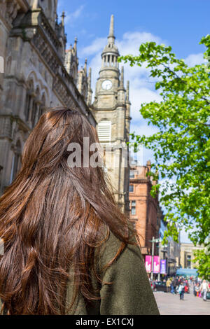 Beautiful, young girl with long brown hair standing with her back to the camera in the streets of big city. Stock Photo