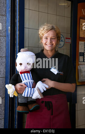 Westhoughton, Lancashire, UK 4th July, 2015 Emma Dawson, aged 23, Manager at Waterfields Bakery at the Yarn Bombing Festival.  WCN group, Rainbow Crafts, it is brought to Westhoughton in a festival of colour, community and entertainment.   By getting young and old, women and men, skilled and novice needlers involved in crocheting, knitting or weaving squares, long strips or coverings to produce street décor an impressive and unusual installations, the town centre for a few days is awash with colour. Cernan Elias/17�Թ����� Live News Stock Photo