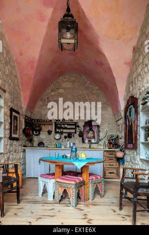 a small kitchen with a high ceiling, stone walls and wooden floor Stock Photo