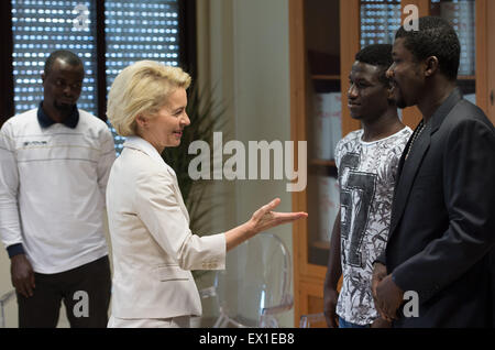 Sicily, Italy. 4th July, 2015. German Defence Minister Ursula von der Leyen (CDU) speaks with refugees from Nigeria and Gambia before her visit to the 'Seenotrettung MED' (lit. sea rescue MED) Bundeswehr mission, off the coast of Sicily, Italy, 4 July 2015. Photo: SOEREN STACHE/DPA/Alamy Live News Stock Photo