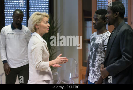 Sicily, Italy. 4th July, 2015. German Defence Minister Ursula von der Leyen (CDU) speaks with refugees from Nigeria and Gambia before her visit to the 'Seenotrettung MED' (lit. sea rescue MED) Bundeswehr mission, off the coast of Sicily, Italy, 4 July 2015. Photo: SOEREN STACHE/DPA/Alamy Live News Stock Photo