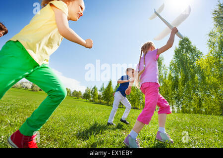 View from below of kids who run, hold airplane toy Stock Photo