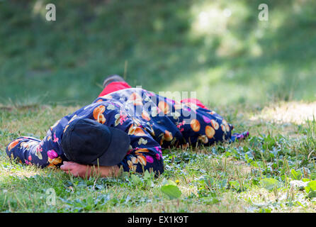 A homeless man is sleeping on a meadow in the center of Sofia. Years after joining the EU Bulgaria is still struggling with grea Stock Photo