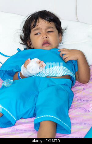 Illness little asian kids crying, asleep on a sickbed in hospital, saline intravenous (IV) on hand Stock Photo