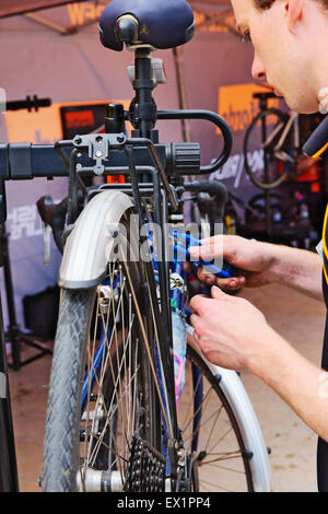 Man adjusting a bicycle while it is held on a mechanics bicycle stand Stock Photo