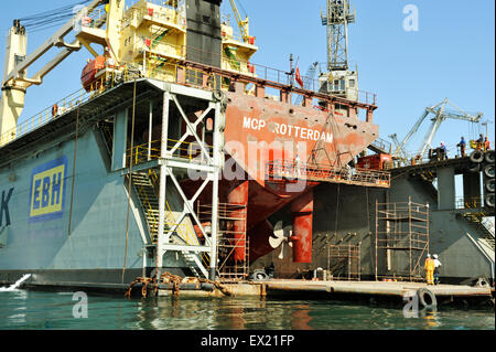 Durban harbour, KwaZulu-Natal, South Africa, workmen painting hull of MCP Rotterdam on EBH floating dry dock, shipyard, people, city, maintenance Stock Photo