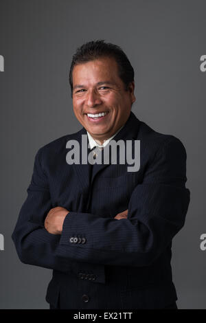 Hispanic business man smiling with arms crossed wearing a business suit posing for a portrait Stock Photo