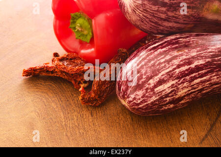 Sun dried tomatoes, red pepper and eggplant on a wooden cutting board. Stock Photo