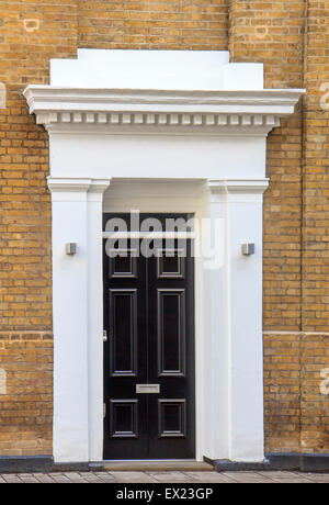 Black door and yeelow brick wall in London Stock Photo