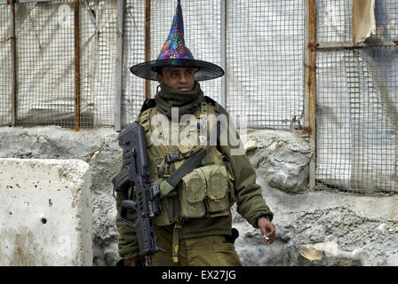 An armed Israeli soldier from the Beta Israel community also known as Ethiopian Jews wearing a clown hat during holiday of Purim in Tel Rumeida Jewish settlement West Bank Israel Stock Photo