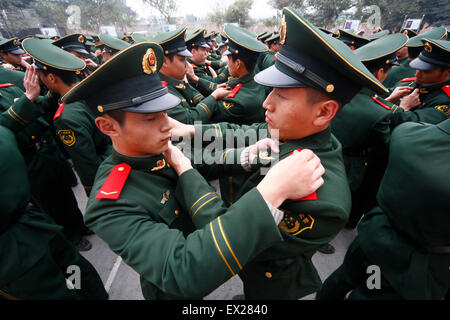 Recruits of the paramilitary police wear badges for each other on their uniforms during a rank-greated ceremony at a military ba Stock Photo
