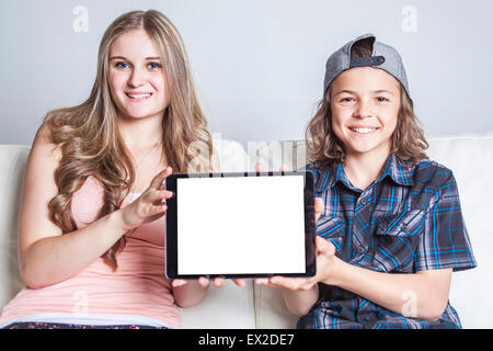 Brother and daughter using digital tablet on sofa at home Stock Photo