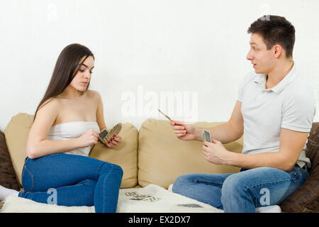 Beutiful couple playing cards indoor. Boyfriend explains game rules to his girlfriend. Couple afternoon relaxing on couch. Circu Stock Photo