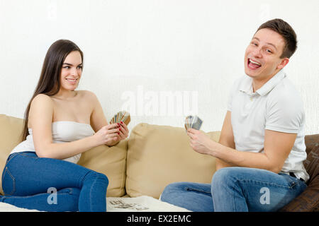 Couple relaxing in relationship playing card game and enjoying. Pretty girl and handsome guy feeling excited while playing poker Stock Photo