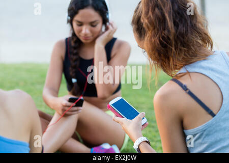 Outdoor portrait of running girls having fun in the park with mobile phone. Stock Photo