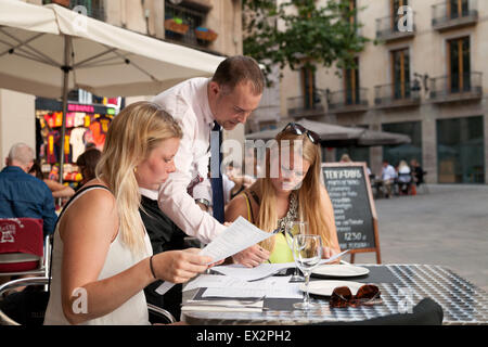 A waiter serving two women at a tapas bar, the Gothic Quarter, Barcelona Spain Europe Stock Photo