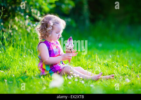 Child eating ice cream. Kids play outdoors enjoying sweet snack on a hot summer day. Children eat icecream. Stock Photo